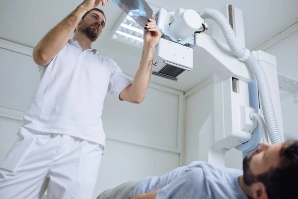 Joven Médico Examinando Radiografías Mientras Paciente Está Acostado Cama Junto — Foto de Stock