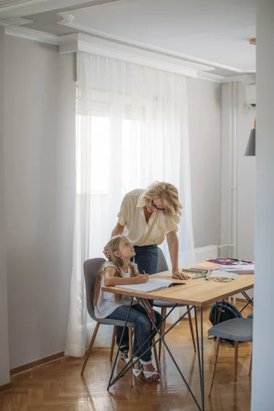 Hermosa Rubia Mujer Caucásica Ayudando Linda Hija Estudiar Casa Imagen De Stock