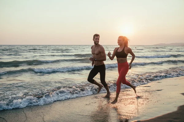 Man och kvinna som körs på sandstranden — Stockfoto