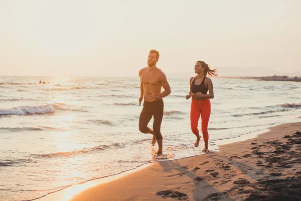 Homem e mulher correndo na praia de areia — Fotografia de Stock