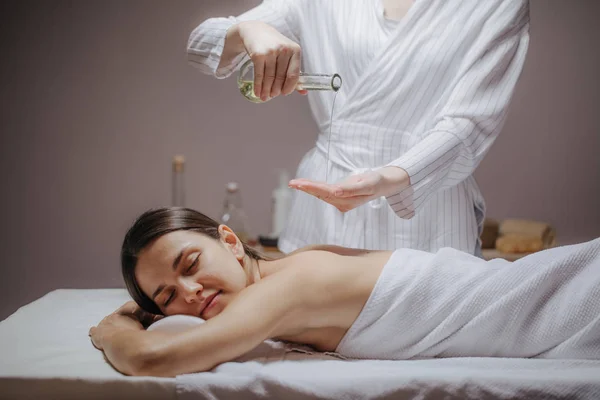 Massagista usando óleo de massagem — Fotografia de Stock