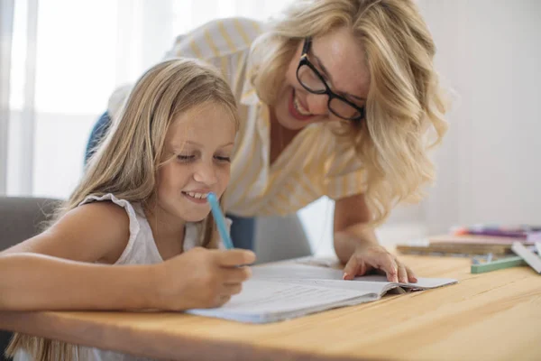 Moeder helpt haar dochter een huiswerk te doen Stockafbeelding