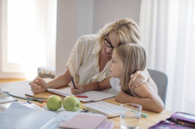 Anne ve kızı okul ödevi yapıyor.