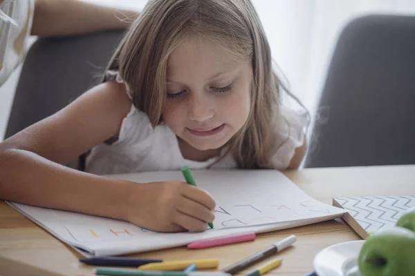 Schoolgirl skriver i sin anteckningsbok — Stockfoto