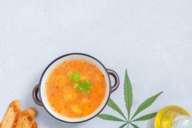 Kenevir aşılamalı gıda konsepti. Marihuana yaprağı, kenevir yağı, ekmek dilimleri ile doğal arka planda esrar sebze çorbası manzarası