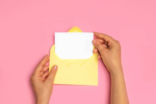女性の手のトップビューを保持空のホワイトカードとオープンイエロー封筒文字 — ストック写真