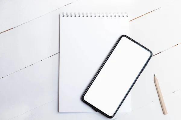 Beyaz ekranlı beyaz ekranlı boş akıllı telefonun beyaz ahşap arka planda üst görünümü