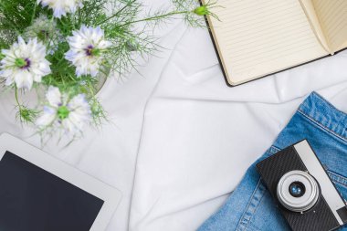 Tablet, klasik kamera, kağıt defter, çiçekler, mavi kot pantolon içeren bir dizi güzellik blogcusu veya etkili aksesuar.