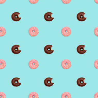 Kusursuz desenli pembe jöleli donutlar ve pastel yeşil arka planda çikolata kaplı ısırılmış çörekler.