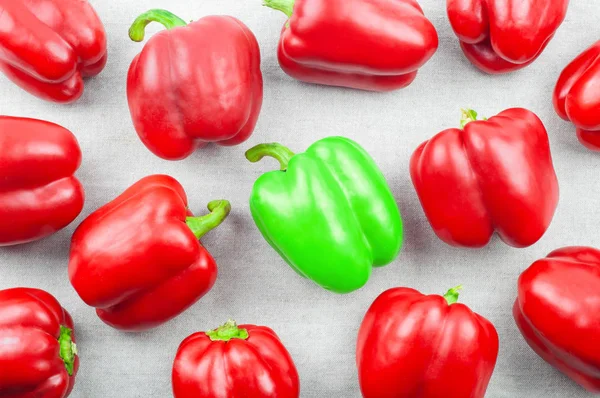 Red and green sweet pepper on white textile background, top view. not everyone — Stock Photo, Image