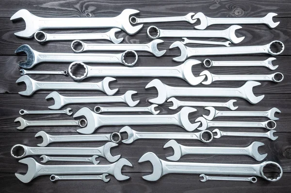 Набор хромированных ключей на темном деревянном верстаке. вид сверху — стоковое фото