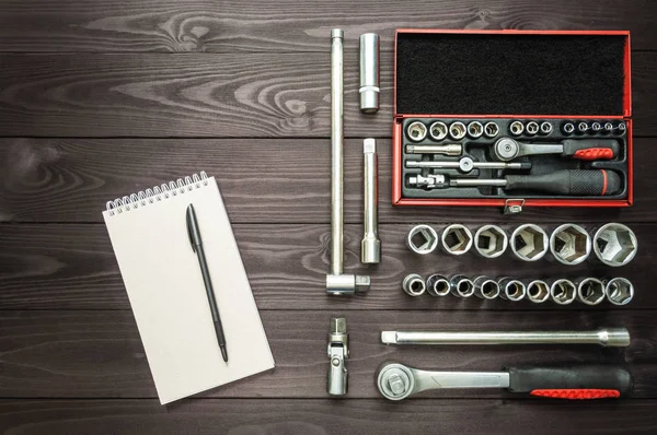 Notebook and set of tools for an auto mechanic on a dark wooden workbench. — Stock Photo, Image