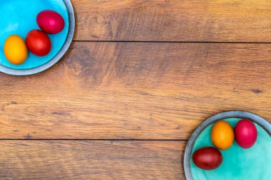 Ahşap arka plan ile iki tabak üzerinde altı renkli Paskalya yumurtaları