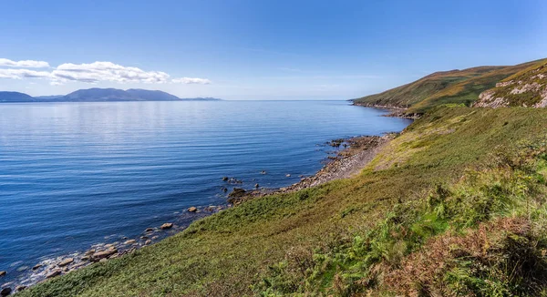 Linha costeira rochosa e montanhas em uma distância com céu azul profundo e mar — Fotografia de Stock