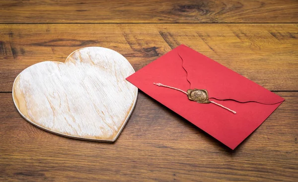 Large white wooden hart and red envelope isolated on vintage oak