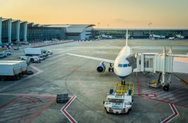 Uçak ve havaalanı servis araçları, günbatımı, tatil kavramı terminal yakınındaki