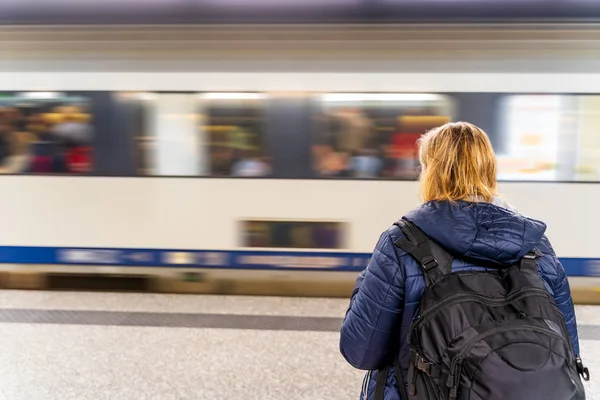 Kvinna väntar på ett tåg i oigenkännlig tunnelbanestation, moti — Stockfoto