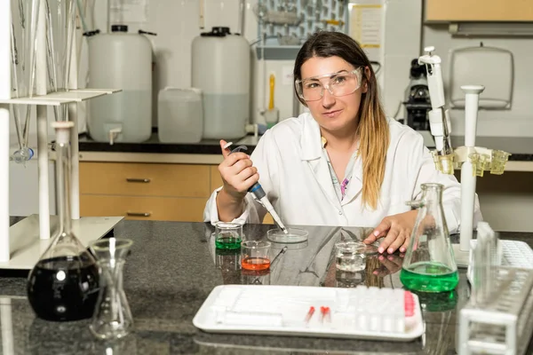 Middle age female laboratory technician  sampling with pipette chemical liquid solution in laboratory