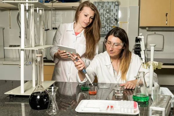 Team of two female laboratory technicians working in chemical or pharmaceutical laboratory