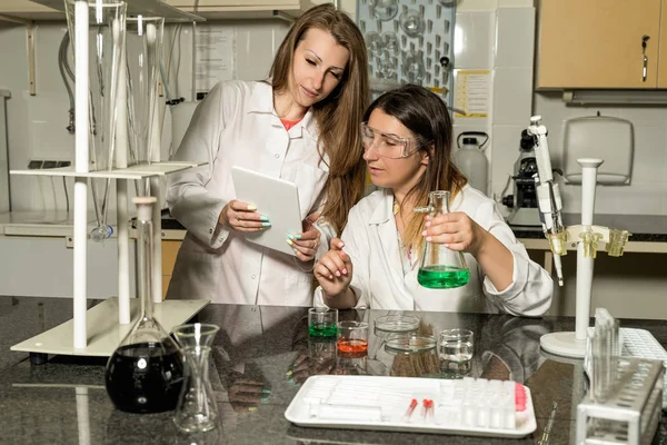 Team of two female laboratory technicians working in chemical or pharmaceutical laboratory