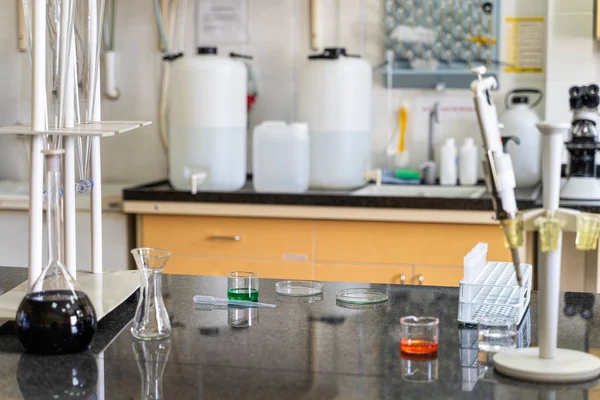 Pipette and colourful chemical liquid solutions in flasks on laboratory worktop — Stock Photo, Image