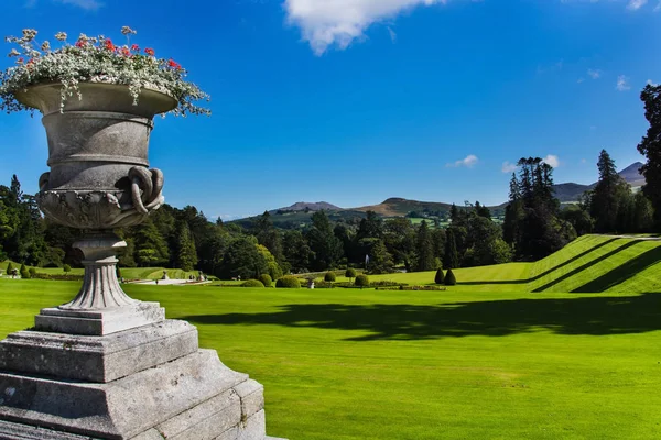 Un pot avec des fleurs et une pelouse verte dans les jardins Powerscourt, montagne Sugerloaf en arrière-plan, Irlande — Photo