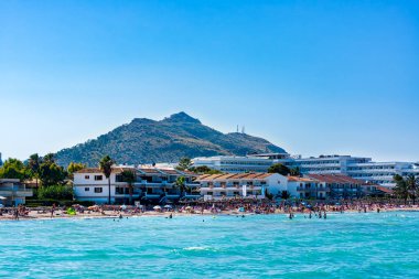 Alcudia plajı, turkuaz deniz, kumlu plaj ve dağ, Mallorca güneş tatil zevk turistler