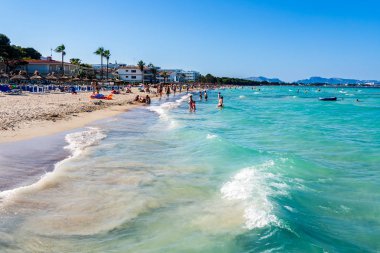 Alcudia plajı, turkuaz deniz ve kumlu plajda güneş lenmenin keyfini çıkaran turistler, Mallorca
