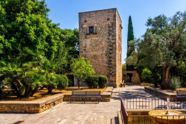 Pollenca, Mallorca palmiye ve ağaçlarla çevrili parkta kare kule,