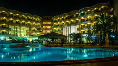 Tropikal bir otelde ya da bir yüzme havuzunun gece fotoğrafı.