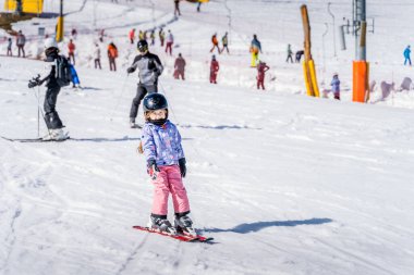 Genç mutlu kayakçı kız yeşil kayak alanında kayak yapmayı öğreniyor. Genç kayakçı kayak pistinde eğleniyor, Bialka Tatrzanska, Tatry, Polonya