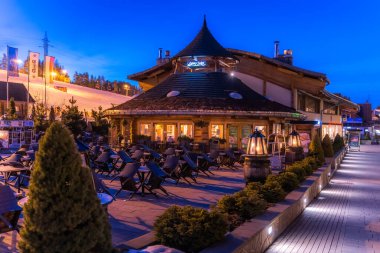 Bialka Tatrzanska, Polonya, Mart 2019 Restoranlar ve kayak limanındaki alışveriş alanı gece vakti Bania. Tatra Dağları 'ndaki popüler kış sporları köyü