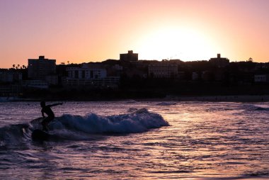 Gün batımında sörf yapan genç bir çocuk.