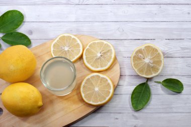 kesme tahtasında servis edilen bir bardak ve limon dilimleri üzerinde taze limon suyu