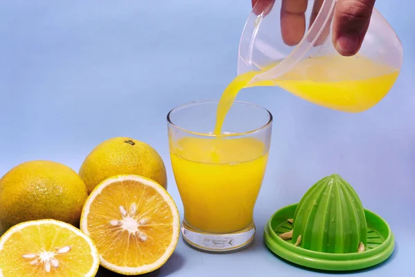 Manos Vertiendo Jugo Naranja Vaso Exprimidor Naranja Aislado Azul — Foto de Stock