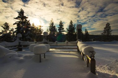 Bir teras ile ormanda doğrudan öğleden sonra güneşte parçalı bulutlu gün Kuzey Lapland şiddetli kar yağışı altında. Laanihovi yakınındaki Saariselka, Finlandiya.