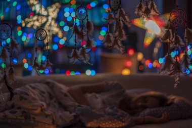 Rüya neon ışık bokeh arka plan, seçici odak karşı kanepede yatak odasında uyuyan bir kız ile Dream yakalayıcılar. Uyku koruması ve güvenli uyku 