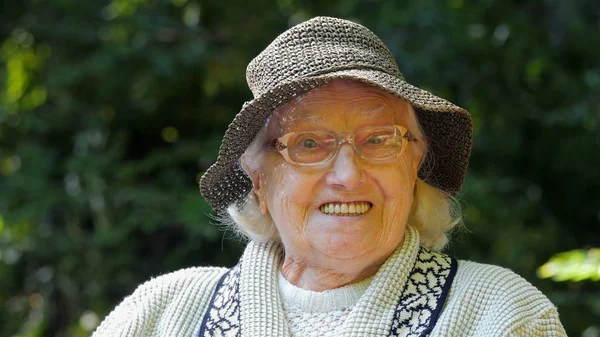 Portrait of an old woman in a hat smiling to the camera