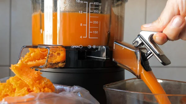 Juicer lento está fazendo cenoura fresca e suco de laranja . — Fotografia de Stock