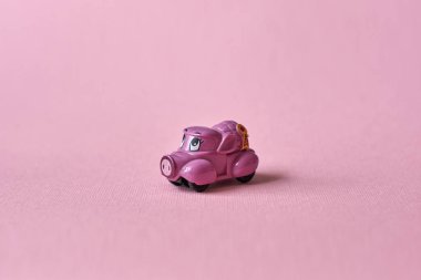 Pembe oyuncak araba pembe bir arka planda ürünleri teslim. Kartpostal 14 Şubat, Sevgililer günü. Çiçek teslimi.