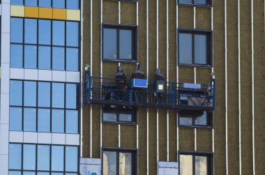 Binanın havalandırılmış cephe ile karşı karşıya. Alüminyum cephe renkli. Yüksek katlı binalar modern cephe. Büyük bir Konut Kompleksi İnşaatı. Askıya alınan inşaat beşik.