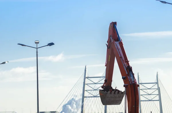 建物のショベル 大規模住宅団地の建設 橋と青空の背景に金属掘削機バケット 建築部門 — ストック写真