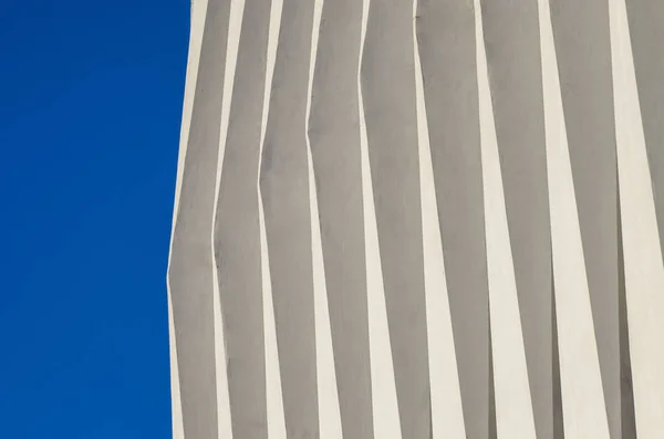 Wave facade of the building. White graphical linear facade of the building. The play of light and shadow. Neutral fashionable background. Light stripes.
