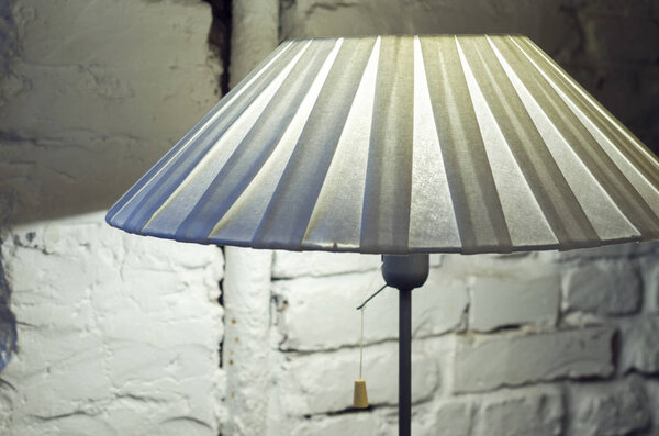 Напольная лампа с тенью. Лампа с белым классическим обожуром против светлой кирпичной стены
.