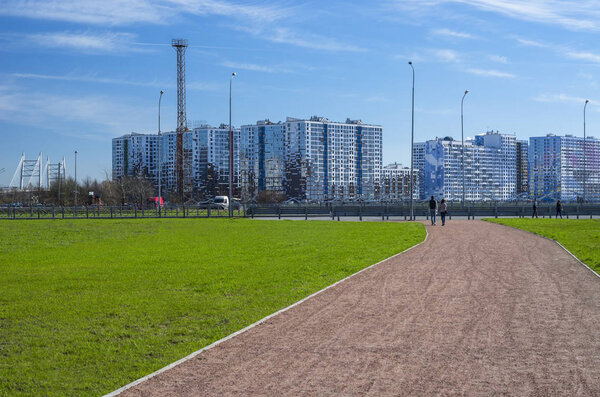 Green lawn and modern apartment buildings. City skyline. Walking zone, comfortable residential quarters. Sunny spring weather. St. Petersburg, Russia, 1 May 2018