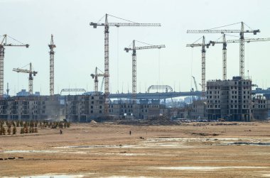 Deniz kenarında bir yerleşim tesisi inşa etmek. Morskaya setinin inşaatı devam ediyor. Suyun kenarındaki kumda evler. Rusya, St. Petersburg, 9 Haziran 2020