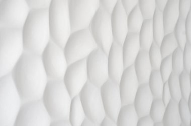 Dalgalı bir dokusu olan beyaz bir duvar. Geometrik desenli alçı taşı panelleri. Tarafsız renklerde kabartmalı duvar. Düzenli tekrarlanan hücreler. Taştan yapılmış dekoratif panel. Kabuğun dokusu..