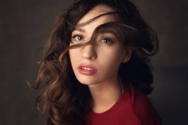 moda fotoğraf curl dudaklarında Studio koyu arka plan üzerinde poz yüz ve kırmızı ile Kırmızı elbiseli esmer saçlı güzel kadın. Duygusal atmosfer ateş. 