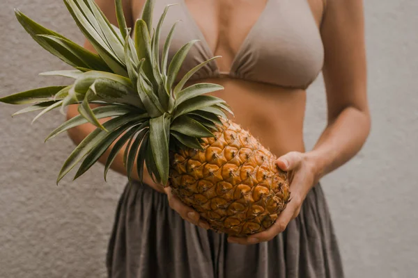 Frau in Boho-Kleidung hält die tropische Frucht Ananas in Händen — Stockfoto