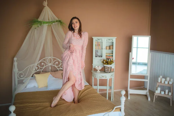 Schöne Frau mit brünetten Haaren in langen sanften rosa Kleid pos — Stockfoto